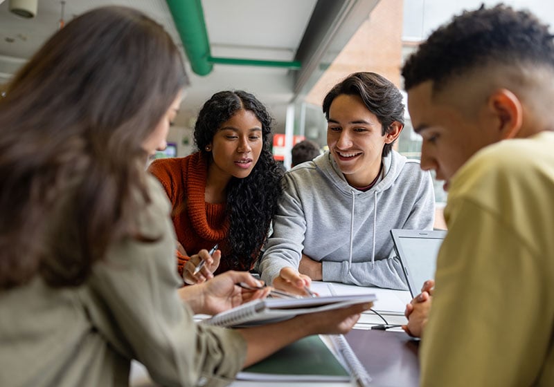 Older students around desk comparing notes