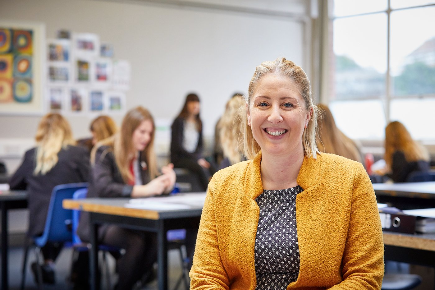 A teacher standing in the classroom with students sat at desks