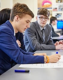 Students working - two males, one writing on paper