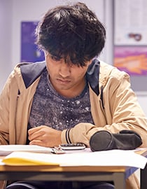 Maths student working at desk with calculator