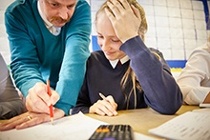 Male maths teacher supporting student with her work
