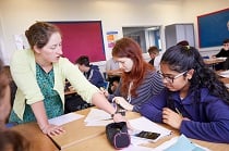 Female maths teacher working with two female maths students at their desk
